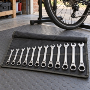 12-piece ratcheting combination spanner set in a canvas tool roll beside a bicycle in a garage